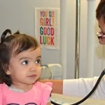 Doctor examining a child in a hospital with medical equipment.