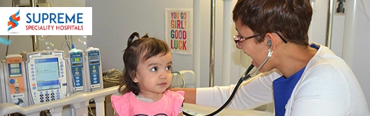 Doctor examining a child in a hospital with medical equipment.